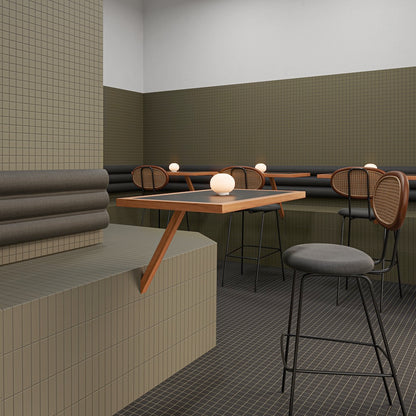 Sitzbereich mit WOW Raster Fliesen in Moss und Basalt, Kombination aus Lines- und Grid-Struktur an Wand und Podest, matte Keramikfliesen in handgemachter Optik mit klarer, geometrischer Raumwirkung.